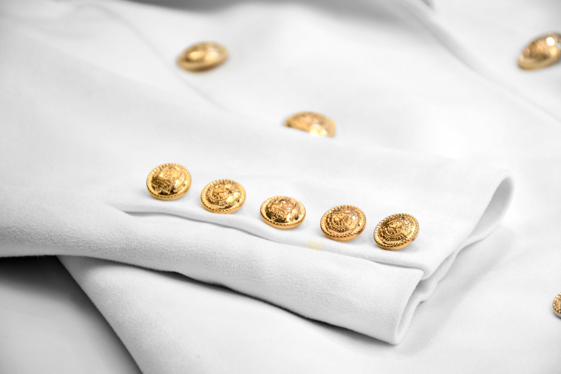 gold buttons on white jacket sleeve