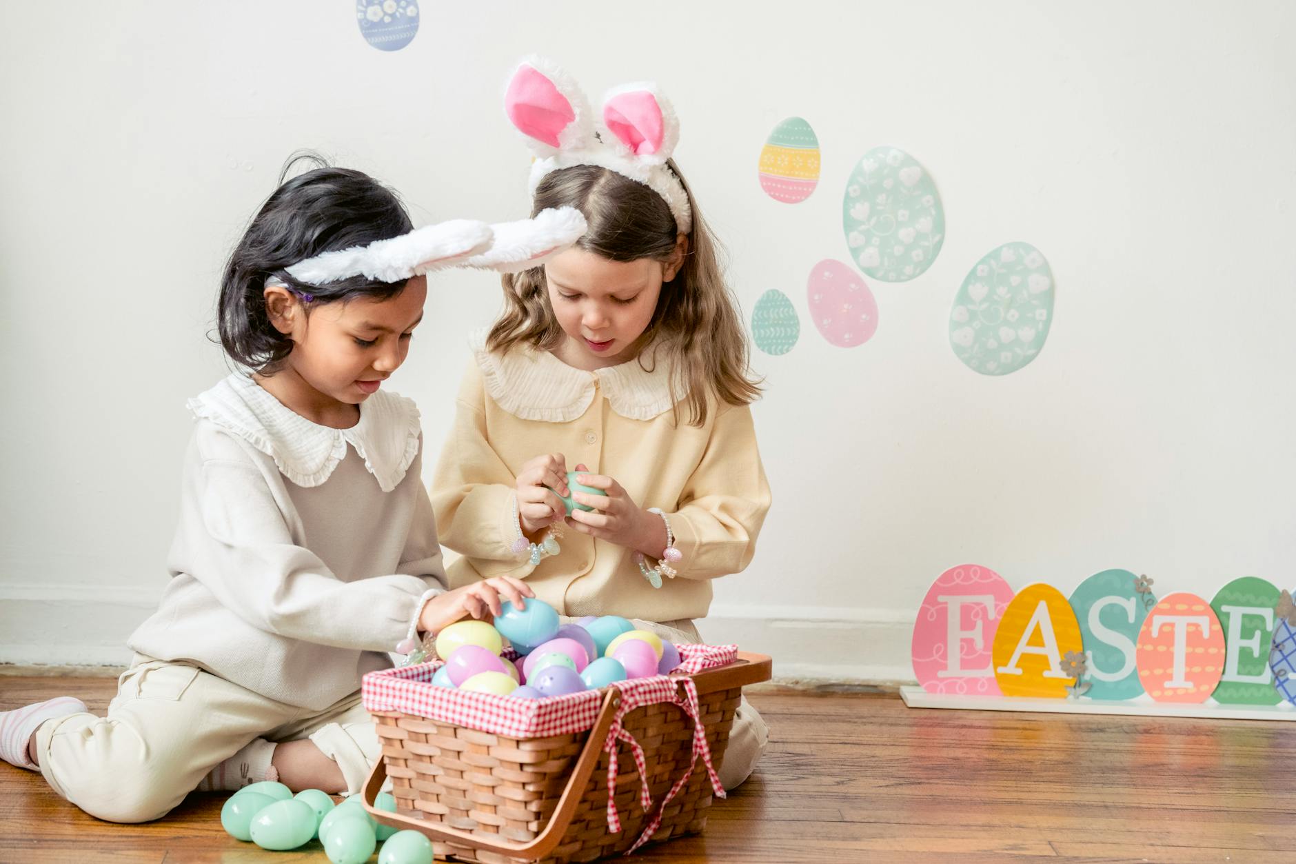 multiracial girls on floor with plastic eggs on easter day