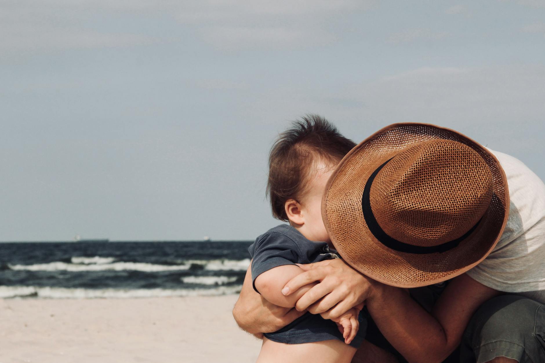 a father hugging his baby on the beach