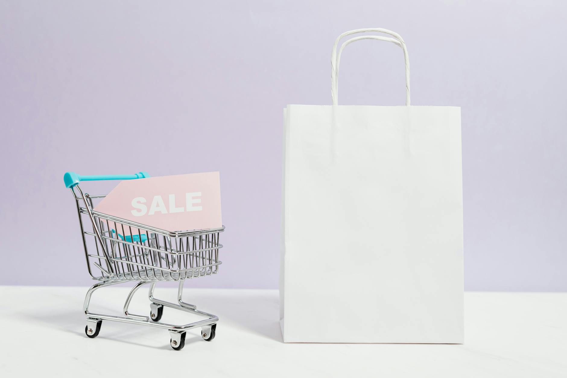 sale sign in a miniature shopping cart and paper bag